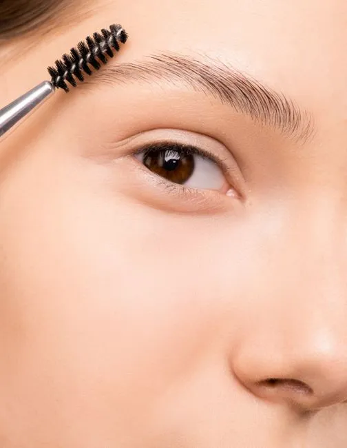 A brow being brushed through with a spoolie after shaping