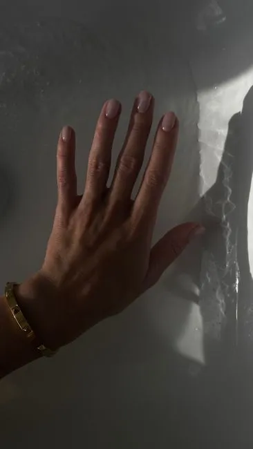 A hand with soft nude nails in warm directional light